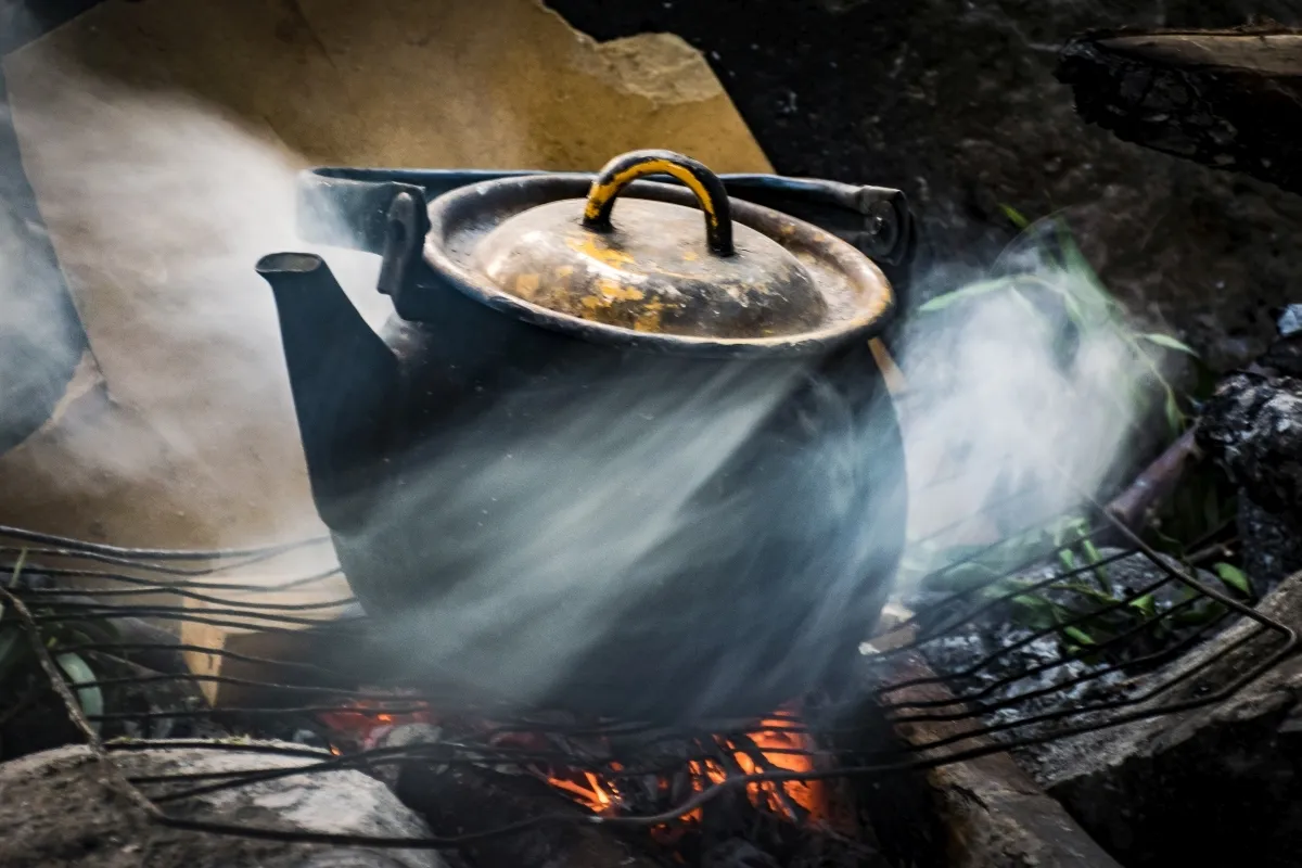 Black kettle steaming over an outdoor fire